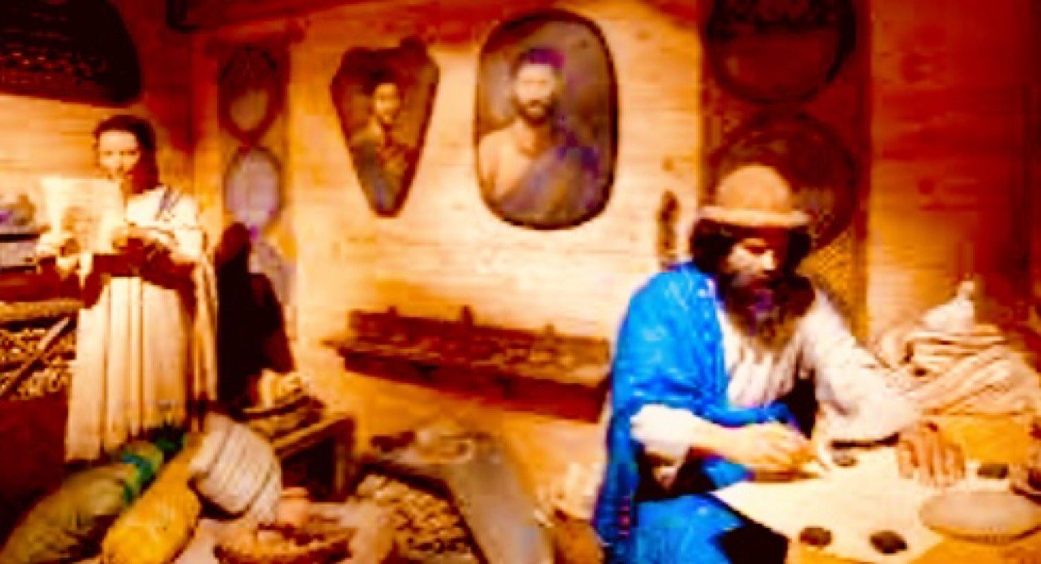 Wide view inside the wooden house: a woman reads at the left, portraits hang on the planks, Noah sits at a table in the knit cap.
